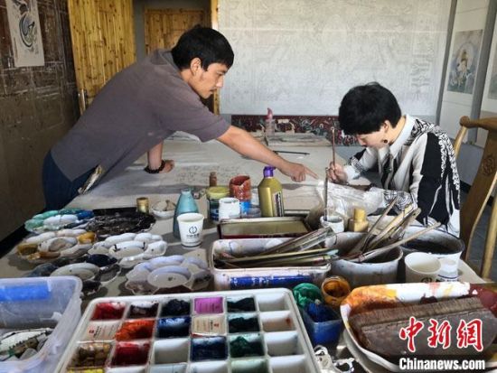圖為2020年8月下旬，敦煌“80后”畫家張杰龍(左)在為云南麗江“學生”莫北講解敦煌壁畫的繪畫技巧?！●T志軍 攝