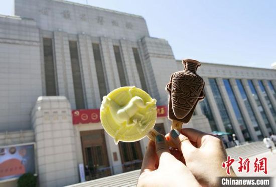 2021年7月30日，游客手拿“銅奔馬”“彩陶瓶”造型的雪糕，在甘肅省博物館前拍照打卡?！「哒?攝