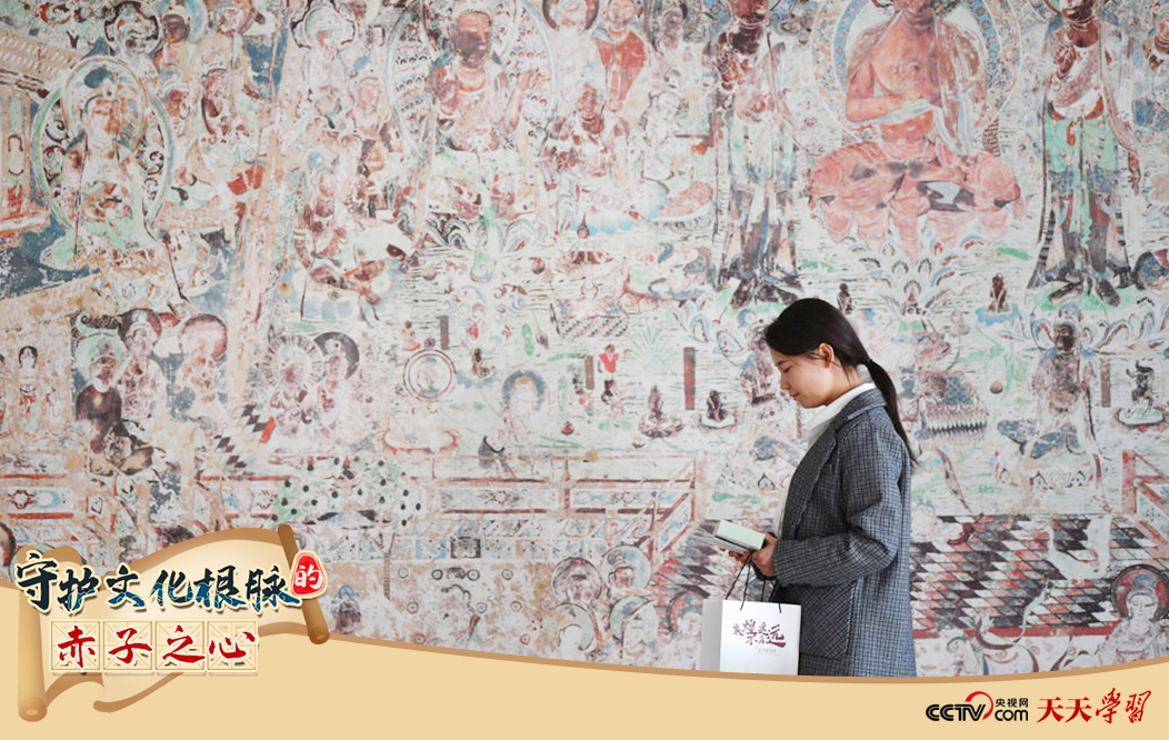2023年4月25日，敦煌研究院文物數(shù)字化保護(hù)團(tuán)隊(duì)創(chuàng)意營銷人員廖雪婷從一幅高保真復(fù)制壁畫前走過。