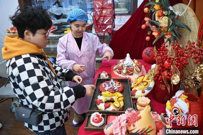 1月25日，隨著春節(jié)臨近，蘭州一花饃店“龍”元素花饃熱銷。圖為工作人員向顧客推薦“龍”元素花饃。九美旦增 攝</p><p>