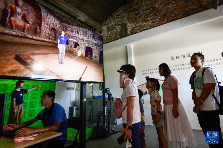 7月22日，游客體驗(yàn)“尋境敦煌——數(shù)字敦煌沉浸展”后，在虛擬演播廳拍攝一段真人與洞窟虛擬場(chǎng)景交互的視頻。新華社記者 郎兵兵 攝</p>
<p>