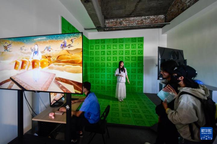 7月22日，游客體驗(yàn)“尋境敦煌——數(shù)字敦煌沉浸展”后，在虛擬演播廳拍攝一段真人與洞窟虛擬場(chǎng)景交互的視頻。新華社記者 郎兵兵 攝</p>
<p>
